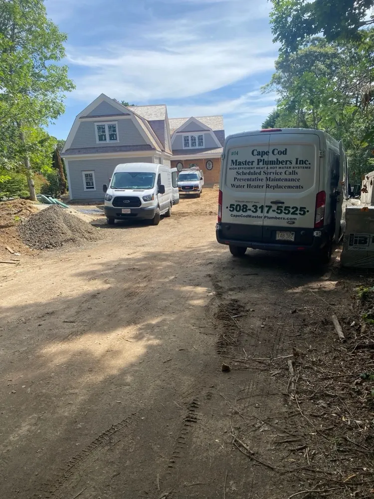Cape Cod Master Plumbers vans parked at a new-construction home on Cape Cod